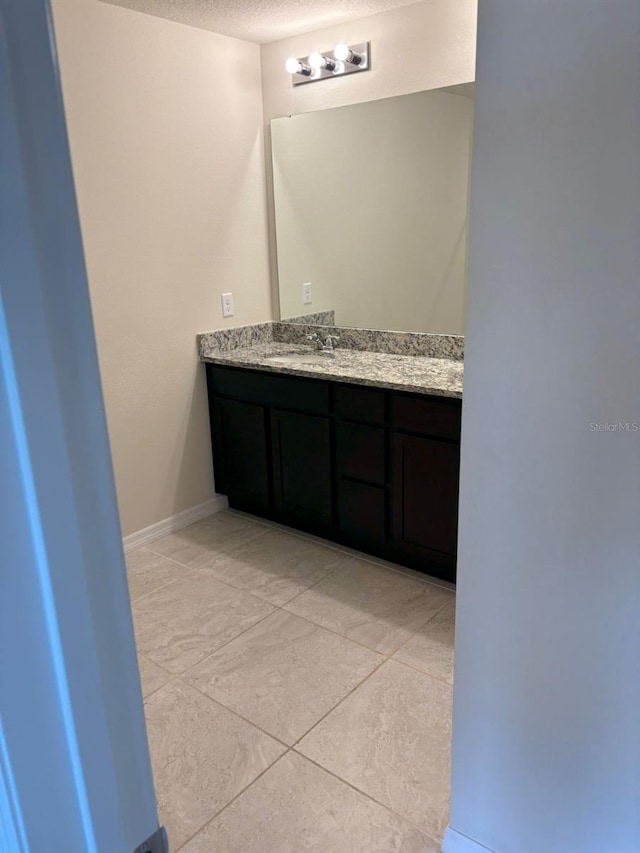 bathroom with tile patterned floors, vanity, and a textured ceiling