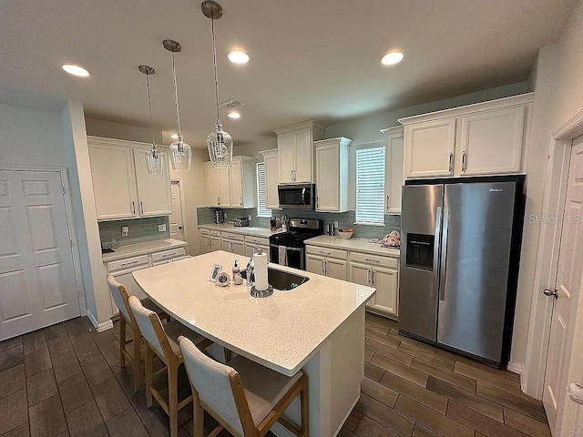 kitchen featuring white cabinetry, sink, decorative light fixtures, and appliances with stainless steel finishes