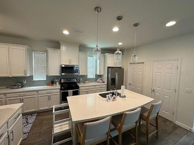 kitchen featuring pendant lighting, a kitchen island, white cabinetry, and stainless steel appliances