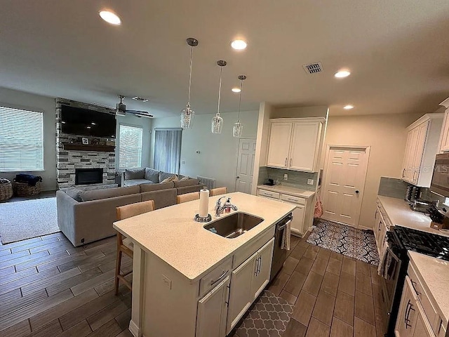 kitchen with white cabinets, an island with sink, dark hardwood / wood-style floors, and sink