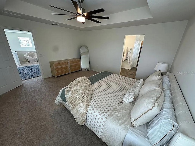 bedroom with carpet flooring, connected bathroom, ceiling fan, and a tray ceiling