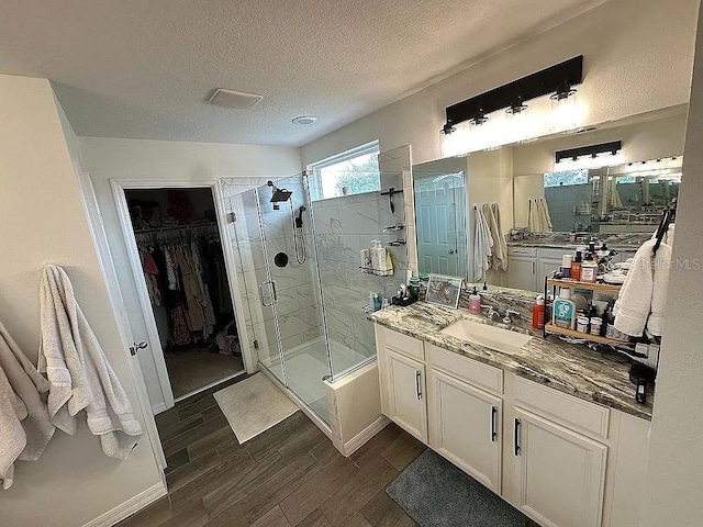 bathroom with wood-type flooring, vanity, a textured ceiling, and a shower with shower door