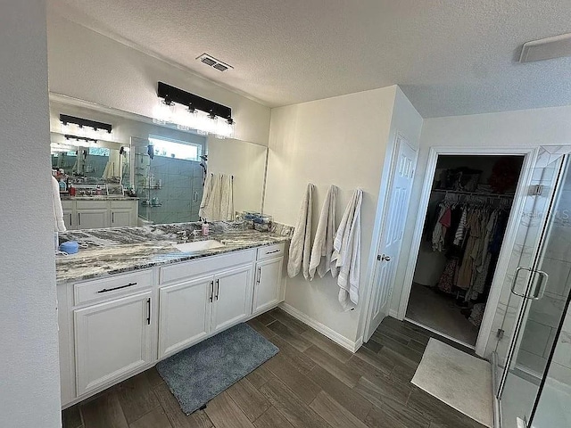 bathroom featuring vanity, hardwood / wood-style floors, a textured ceiling, and a shower with shower door