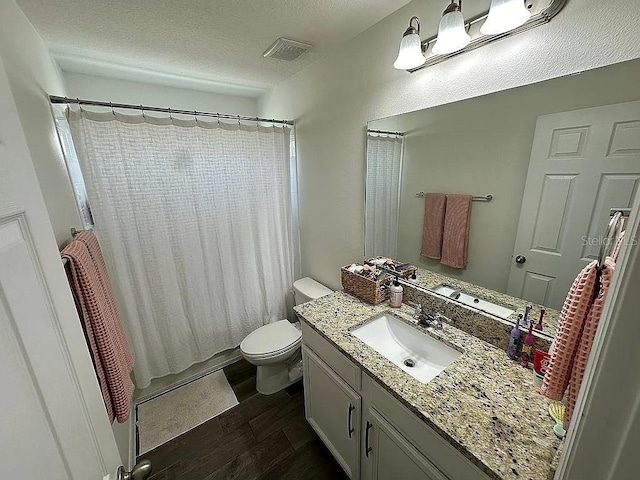 bathroom with wood-type flooring, vanity, a textured ceiling, and toilet