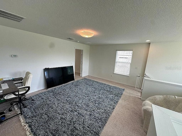 carpeted home office featuring a textured ceiling