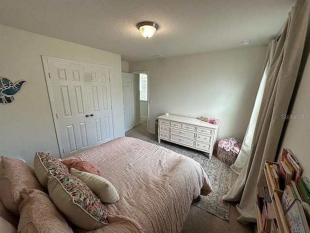 carpeted bedroom featuring a textured ceiling and a closet