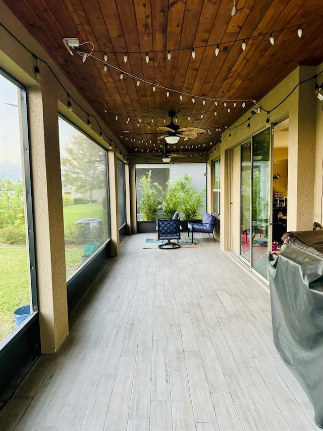 sunroom / solarium featuring a wealth of natural light, ceiling fan, and wood ceiling