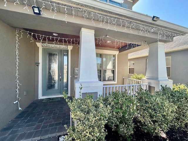 doorway to property featuring a porch and stucco siding