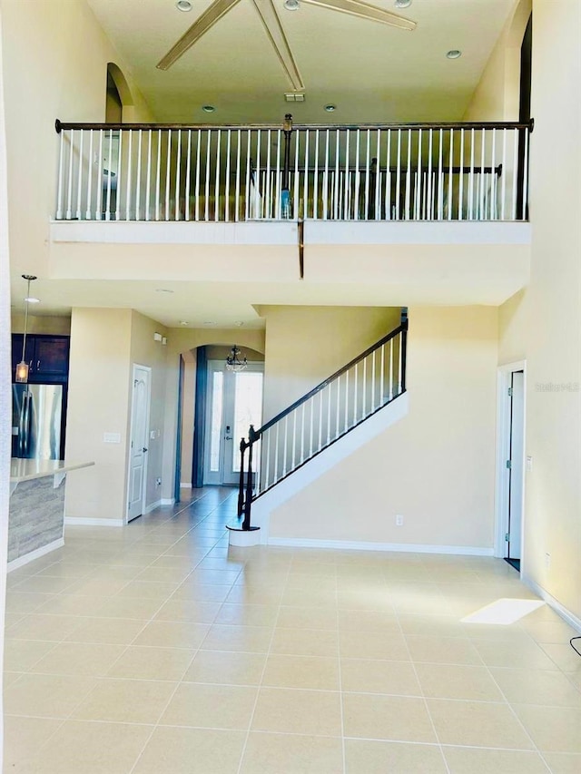 staircase featuring tile patterned floors, baseboards, and a towering ceiling