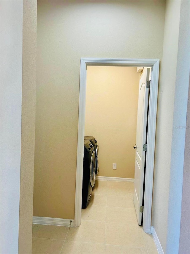 clothes washing area featuring laundry area, light tile patterned floors, separate washer and dryer, and baseboards