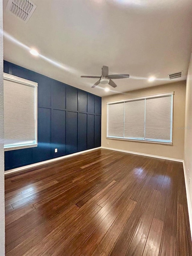 unfurnished room with visible vents, a ceiling fan, and wood-type flooring