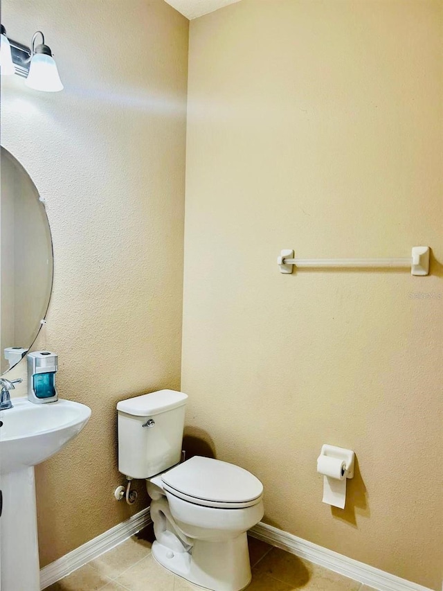 bathroom with tile patterned floors, baseboards, and toilet