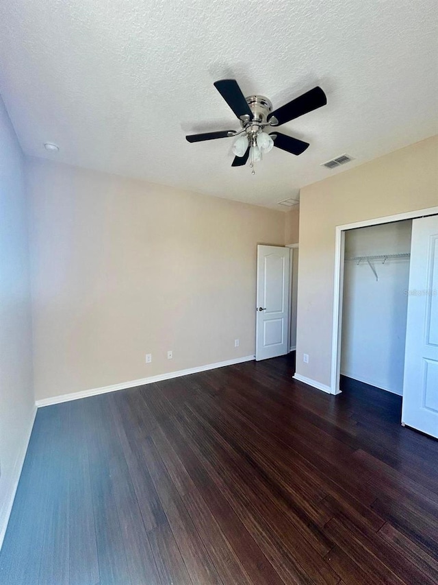 unfurnished bedroom featuring visible vents, a ceiling fan, baseboards, and dark wood-style flooring