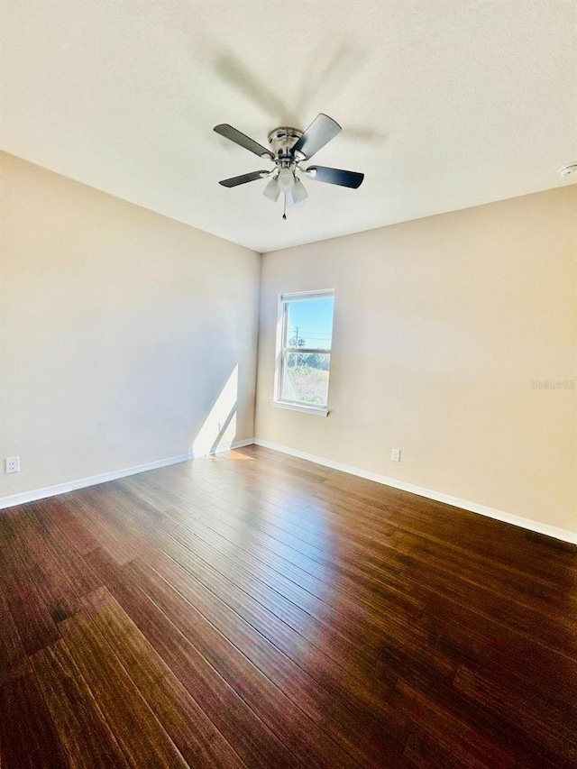 empty room featuring baseboards, wood finished floors, and a ceiling fan