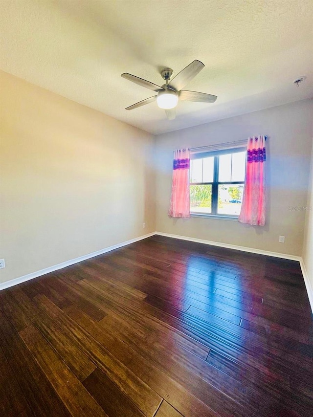 unfurnished room featuring a ceiling fan, baseboards, and wood-type flooring