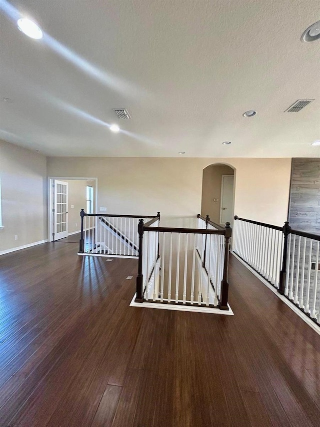 spare room featuring visible vents, a textured ceiling, baseboards, and wood finished floors