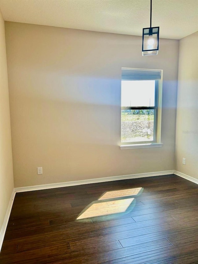 empty room featuring dark wood-type flooring and baseboards