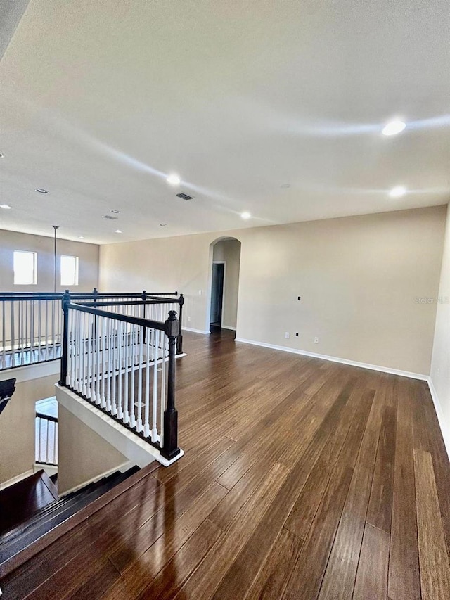 empty room with hardwood / wood-style floors, baseboards, and visible vents