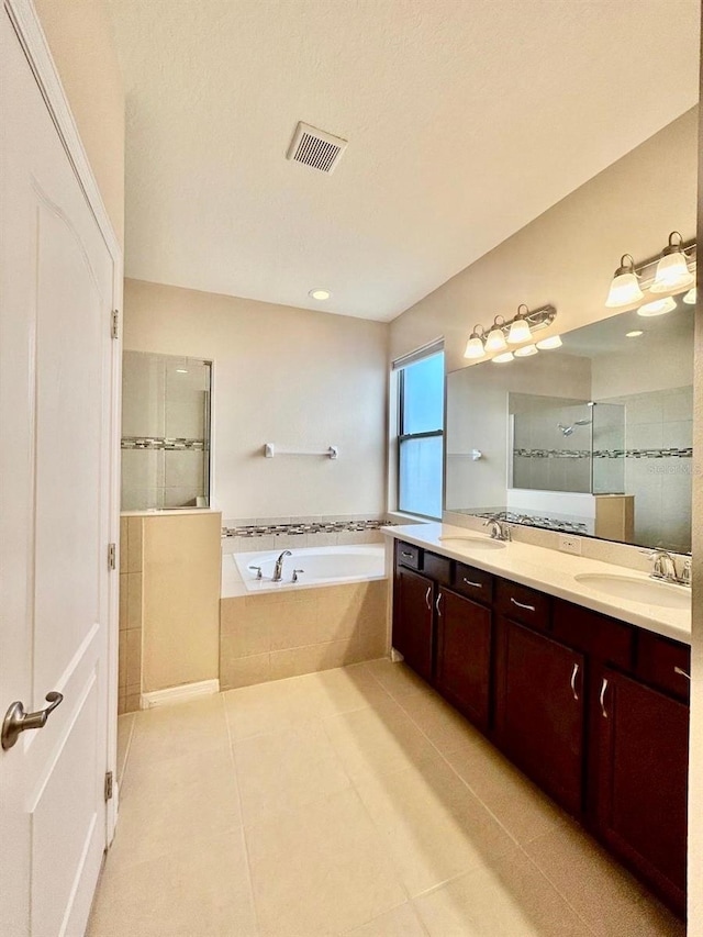 full bathroom featuring a bath, a shower stall, tile patterned floors, and a sink