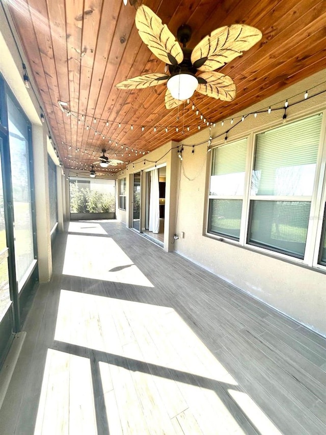 unfurnished sunroom with wood ceiling and ceiling fan