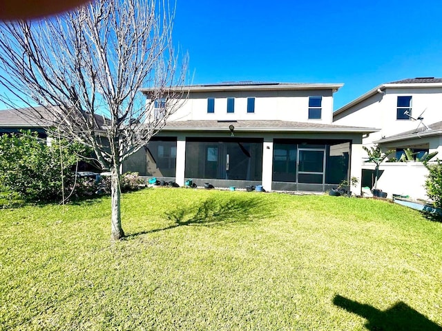 rear view of property featuring a lawn, solar panels, fence, and a sunroom