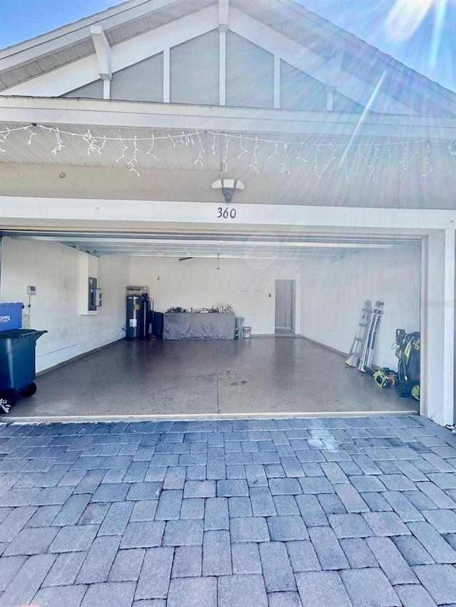 garage with electric panel, electric water heater, and decorative driveway