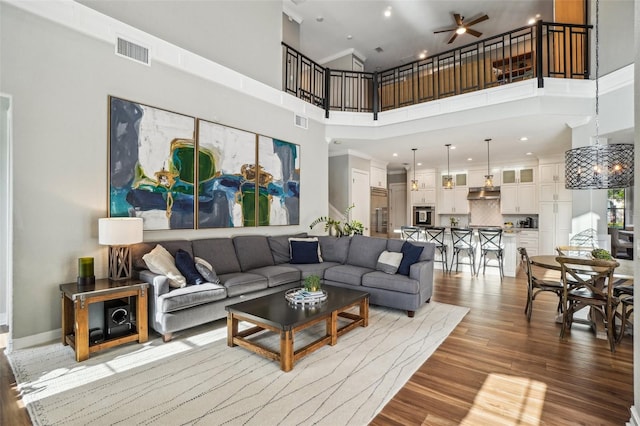 living room with a high ceiling, hardwood / wood-style floors, and ceiling fan