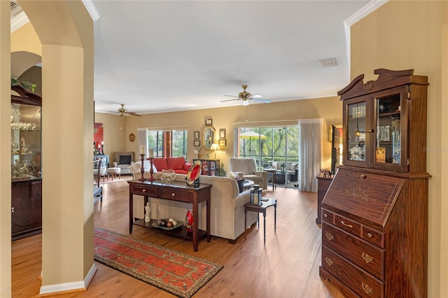 living room with light wood-type flooring, plenty of natural light, and crown molding