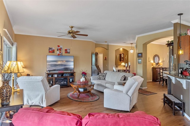 living room featuring light wood-type flooring, ceiling fan, and crown molding