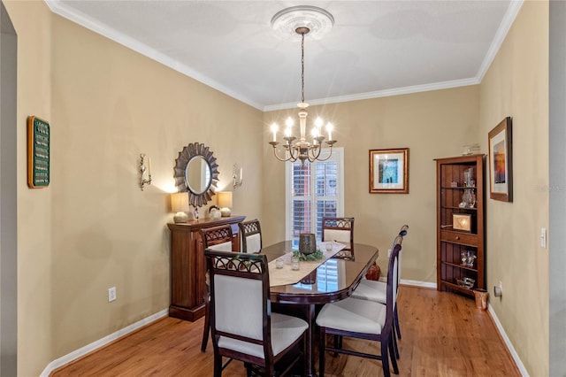 dining room with light hardwood / wood-style floors, ornamental molding, and a chandelier