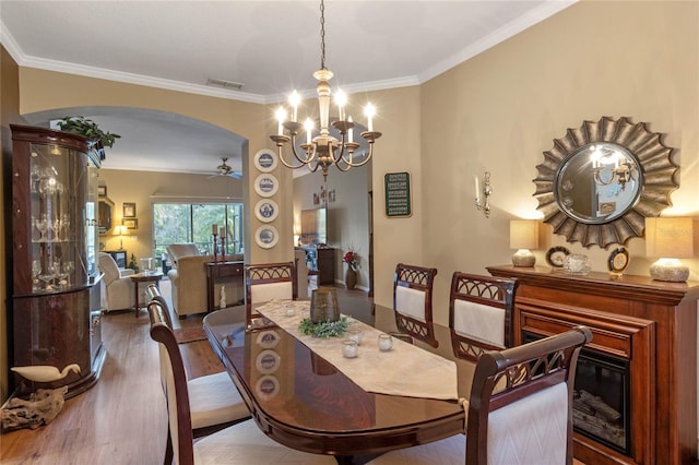 dining room featuring ceiling fan with notable chandelier, crown molding, and dark wood-type flooring