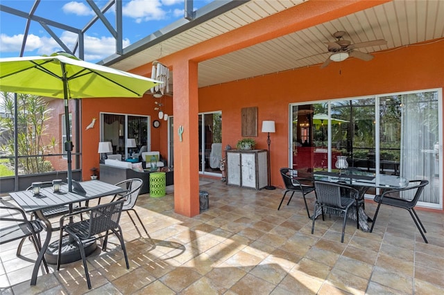 view of patio featuring ceiling fan, an outdoor hangout area, and glass enclosure