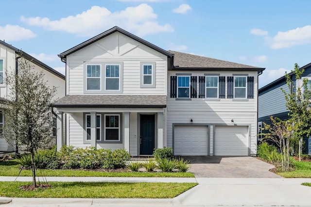 traditional-style home with a garage, a shingled roof, and decorative driveway