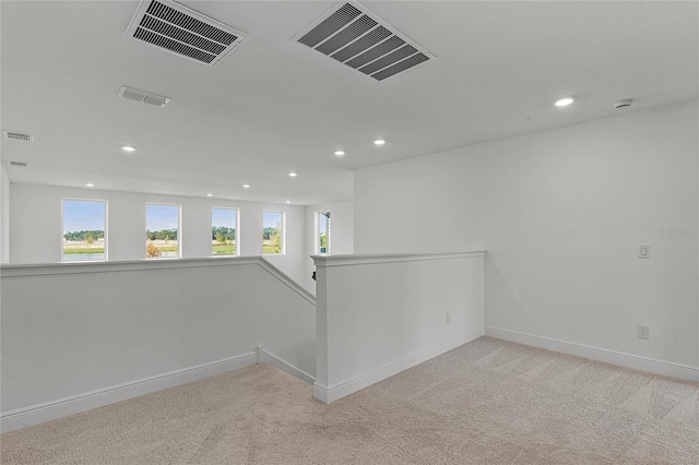 spare room featuring a healthy amount of sunlight, visible vents, and light carpet