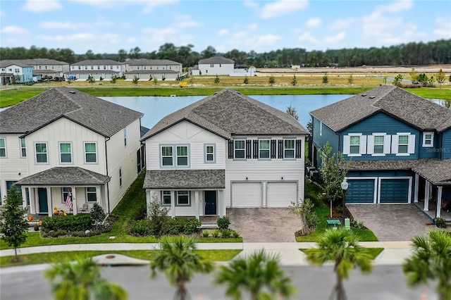 traditional-style house featuring a garage, a water view, a residential view, and decorative driveway