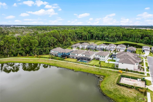 drone / aerial view with a residential view, a wooded view, and a water view