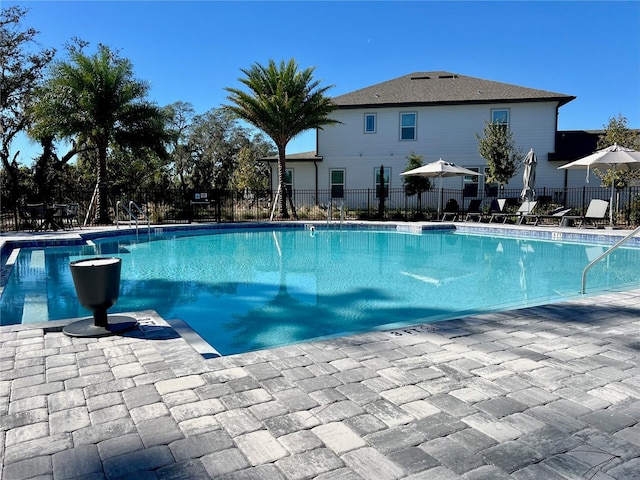 community pool with a patio area and fence