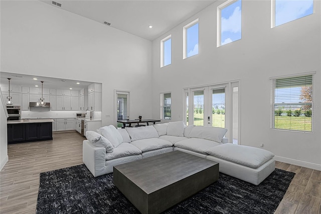 living area featuring visible vents, baseboards, recessed lighting, light wood-style floors, and french doors