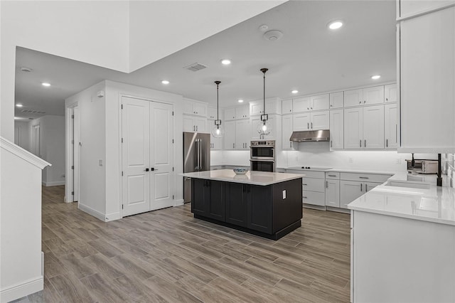 kitchen featuring white cabinetry, visible vents, under cabinet range hood, and a kitchen island