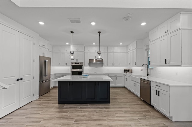 kitchen featuring a kitchen island, a sink, visible vents, light countertops, and appliances with stainless steel finishes