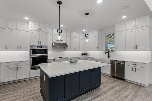 kitchen featuring light countertops, appliances with stainless steel finishes, white cabinets, a sink, and under cabinet range hood