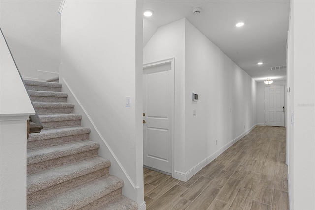 stairs with baseboards, wood finished floors, visible vents, and recessed lighting