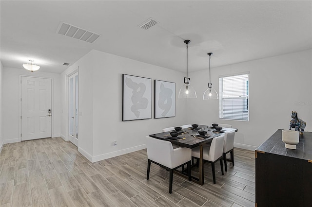 dining room with light wood-type flooring, baseboards, and visible vents