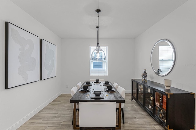 dining space featuring light wood-style flooring and baseboards