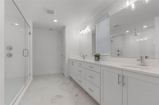 bathroom with double vanity, marble finish floor, a shower stall, and a sink