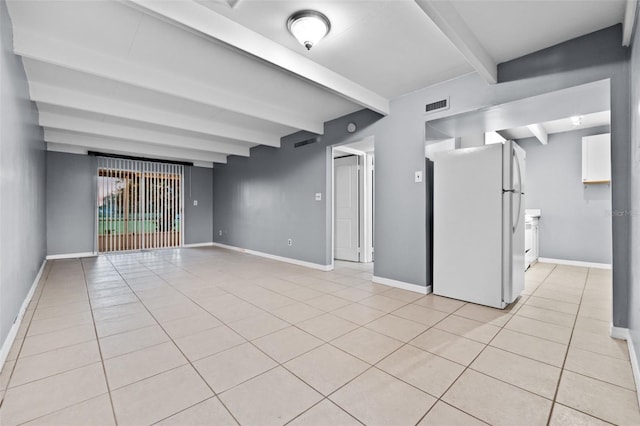 unfurnished room with beamed ceiling and light tile patterned floors