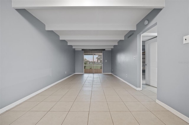 tiled empty room featuring beamed ceiling