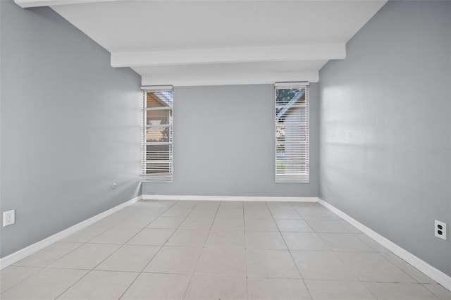 tiled spare room featuring beamed ceiling and a wealth of natural light