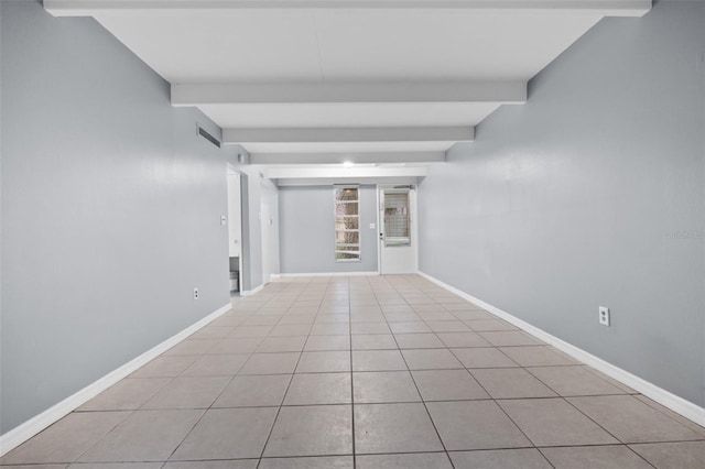 spare room featuring beamed ceiling and light tile patterned floors