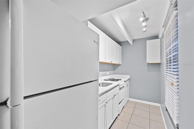 kitchen with white cabinets, light tile patterned flooring, sink, and white fridge